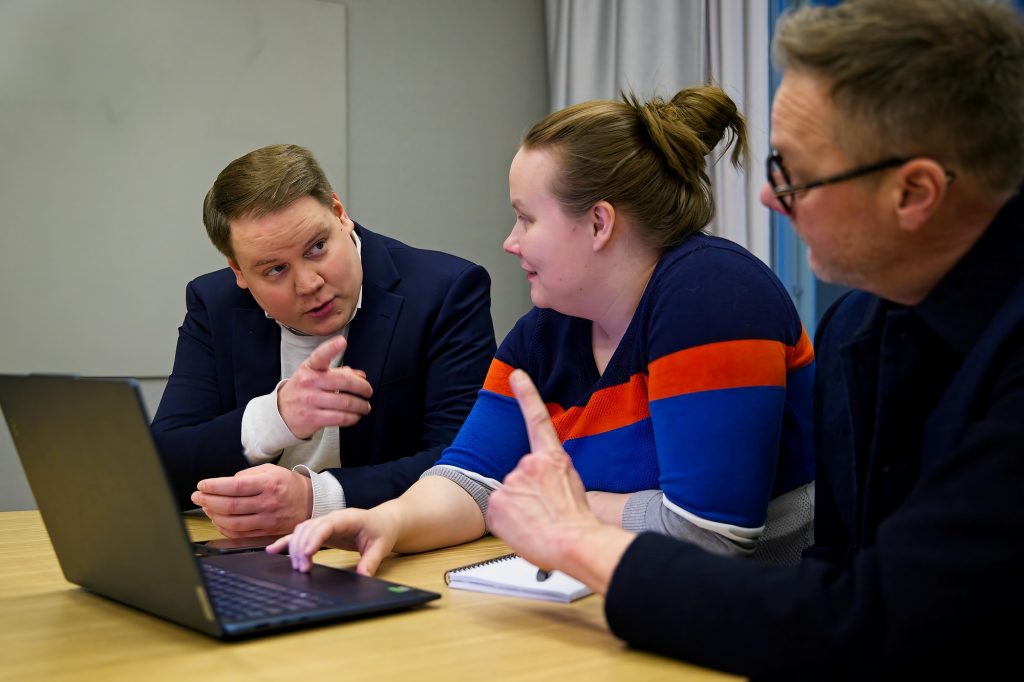 Kalle Saleva ja Mikko Heiskanen osoittavat toisiaan Johanna Vilkunan ihmetellessä välissä tietokoneella